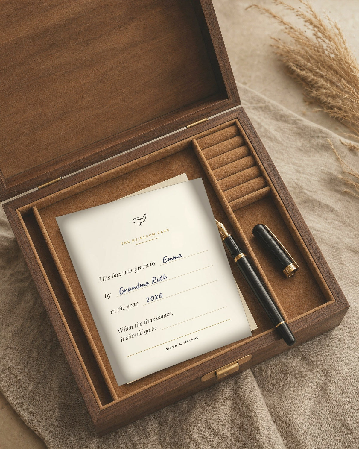 The Heirloom Card resting on the tray of an open walnut box, filled in by hand, with a fountain pen